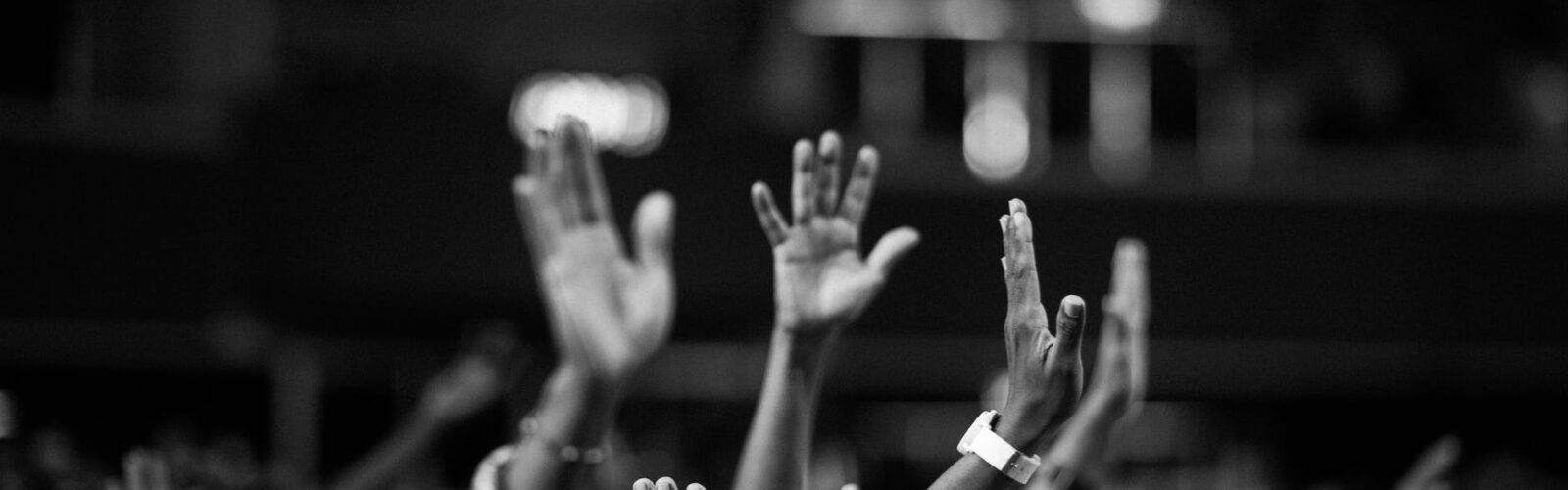 grayscale photography of people raising hands