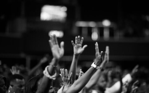 grayscale photography of people raising hands